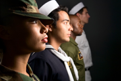 Four military personnel stand in a row, each wearing different uniforms, facing to the right. Their presence reflects both tradition and change, hinting at the evolving role of cannabis reform within society and military history. CA Norml