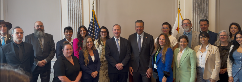 Members of the Cannabis Unity Coalition and Cal NORML stand together in business attire during Lobby Day, smiling in a formal room with U.S. and California flags behind them. Ca NORML