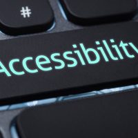 A close-up of a keyboard with a large black key labeled “Accessibility” in glowing blue letters, highlighting the importance of ADA compliance for any cannabis website. Ca NORML